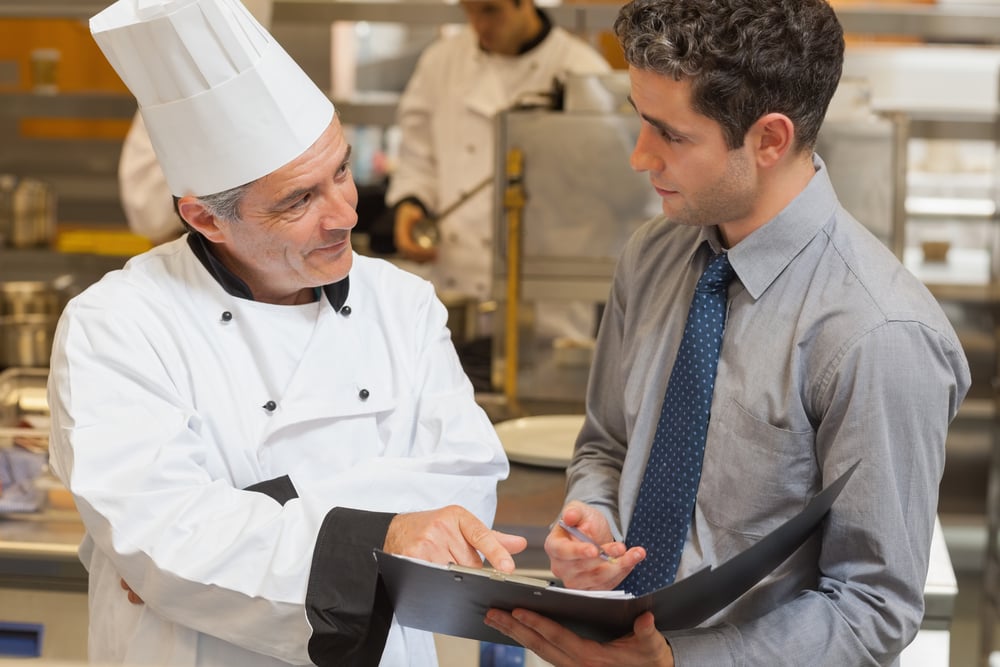Waiter and chef discussing the menu in the kitchen Waiter and chef discussing the menu in the kitchen